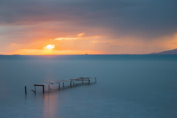 Obraz premium Wooden pier built into the sea and helping fishing, sunset colors and light