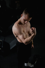 Fototapeta na wymiar Male bodybuilder posing and showing his muscles to the camera in a gym with exercise equipment