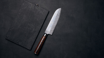 Empty black wooden cutting board and kitchen knife on black stoel, top view
