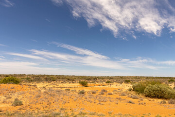 view into the australian landscape with clouds in the sky and a few bushes on the ground, travel australia