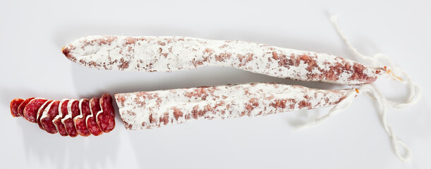 Traditional Catalan thin dry cured pork sausage Fuet with sliced pieces on white background..