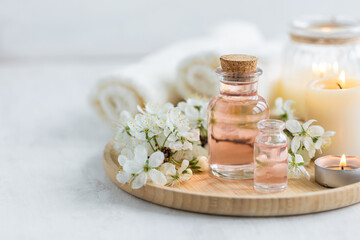 Concept of pure natural organic ingredients, flowers, herbal extracts in cosmetic beauty products. Perfumery, home fragrance with the scent of blooming spring flowers. Candles, bamboo tray