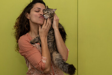 Latin American woman holds in her arms and plays affectionately with her cat