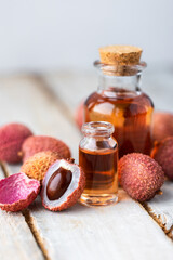 Glass bottles with pure organic essential litchi oil on wooden background. Concept of natural ingredients for beauty treatment, skin care, massage. Exotic fruit extract
