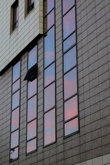 Office building facade with glass windows reflecting sunset sky colors in Bucharest