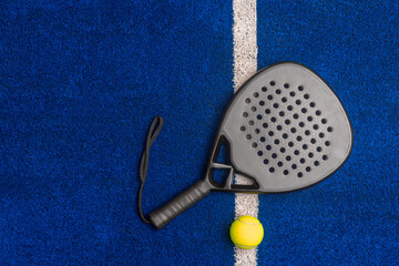 Black professional paddle tennis racket and ball on blue background. Horizontal sport theme poster,...