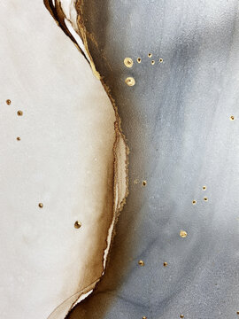 Abstract brown art with gold and gray &mdash; beige background with golden paint. Beautiful smudges and stains made with alcohol ink. Brown fluid art texture resembles brown marble, watercolor or aquarelle.