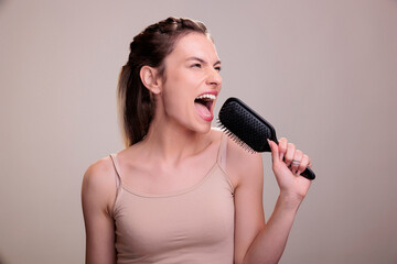 Beautiful woman singing loudly in hairbrush during hairstyle routine. Attractive young caucasian...