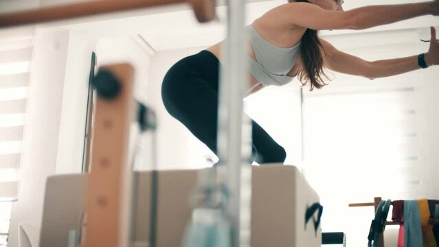 A beautiful slim woman practices pilates on the frame reformer
