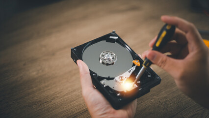 Close up of hard disk internal mechanism hardware. HDD in hand with a screwdriver