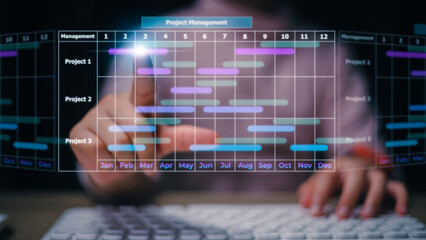 Project manager working on laptop and updating tasks and milestones progress planning with Gantt chart scheduling interface for the company on virtual screen. Business Project Management System.