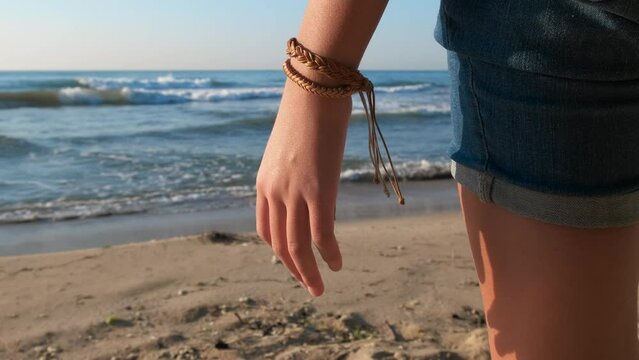 Girl with fenya by sea. A view of girl wearing a pretty fenya on her hand on the sandy beach against blue sea in summer.