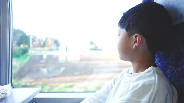 電車の窓から外を見る小学生の男の子