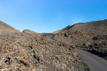 Timanfaya National Park, mountains of fire at Lanzarote, Canary Islands, Spain. Road through lava river flows, lunar landscape on planet earth.