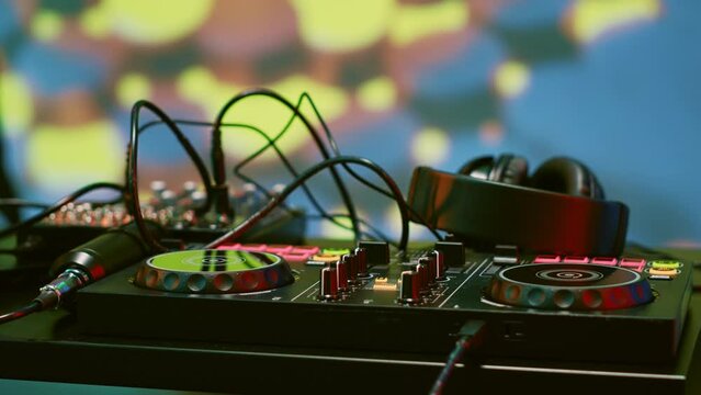 Mixing DJ station for live music on stage at discotheque, funky underground event at nightclub. Empty club and dance floor with audio panel equipment, disco party with spotlights. Close up.
