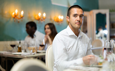 Portrait of man with glass of red wine waiting for woman in a restaurant