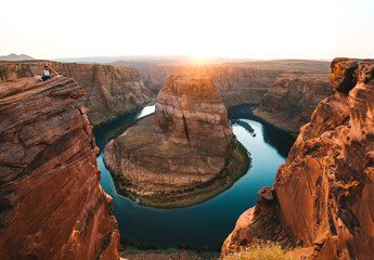 Young woman sitting in the edge of the Horseshoe Bend admiring the landscape. Page, Arizona, United...