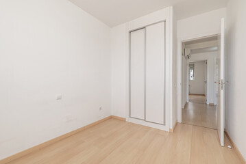 An empty room in an apartment with a built-in wardrobe with white sliding doors