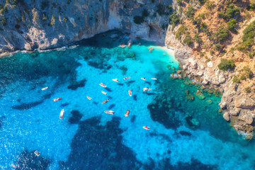 Top drone view of boats and yacths in transparent azure water at sunset. Aerial view of boats in clear blue sea in Sardinia, Italy. Beautiful tropical seascape. Nature. Rocky sea coast. Sea lagoon