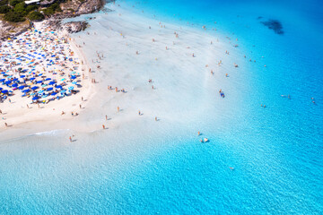 Aerial view of amazing sea coast. Top view from drone of beach with white sand, umbrellas, swimming people in blue transparent water at sunny day. Summer in La Pelosa beach, Sardinia, Italy. Tropical