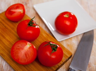 Fresh juicy organic tomatoes on wooden kitchen table