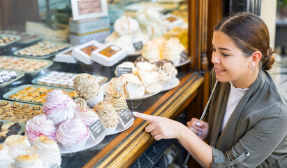 Curious female tourist looking at tasty cupcakes outdoor display