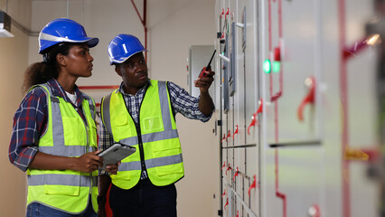 Male and Female electrical engineer team working in control room, Electrical power supply for...