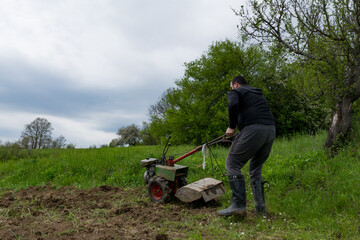 A man operates a motor cultivator in the field, tilling the plowed land and preparing it for sowing...