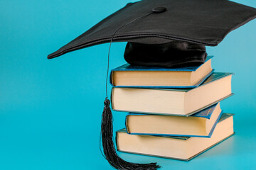 Education and science concept.Graduation Cap with a stack of books.Books with blue covers stack and student hat on blue background. Knowledge and education.Books set and Literature and reading 
