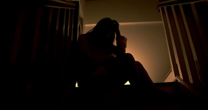 A lonely woman is sitting on the stairs at night . This concept use for symptoms of stress, major depressive disorder (MDD), psychotic symptoms.

