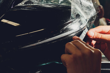 Close up of paint protection film installation on side mirror of modern luxury car. PPF is...