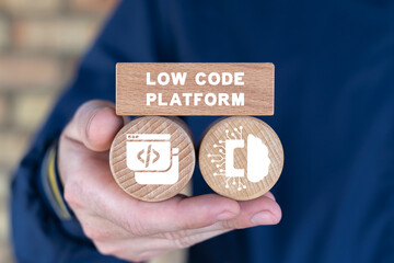 Man holding wooden cubes with icons and inscription: LOW CODE PLATFORM. Concept of Low Code Software Development Platform Technology.