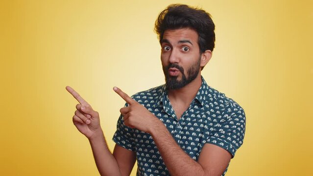 Call us, here is contact number. Handsome bearded indian man in shirt looking at camera doing phone gesture like says hey you call me back conversation. Hindu guy isolated on yellow background, indoor