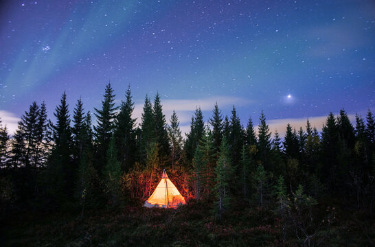 Glowing tent pitched under the clear night sky with stars
