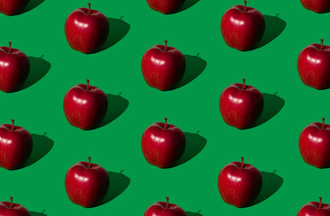 Trendy fruit pattern made of red apples on bold green background. Nature creative concept. Minimal layout.