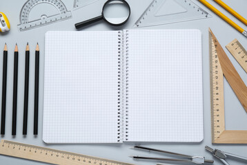 Different rulers, notebook and other stationery for drawing on light grey background, flat lay