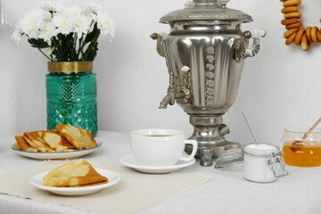 Vintage samovar, cup of hot drink and snacks served on table. Traditional Russian tea ceremony