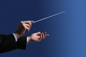 Professional conductor with baton on blue background, closeup