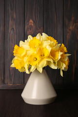 Bouquet of beautiful yellow daffodils in vase on wooden table