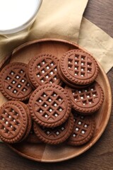 Tasty chocolate sandwich cookies with cream on wooden table, top view