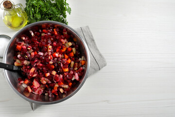 Delicious fresh vinaigrette salad and ingredients on white wooden table, flat lay. Space for text