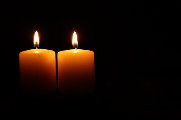 Burning wax candles on black background, closeup. Space for text