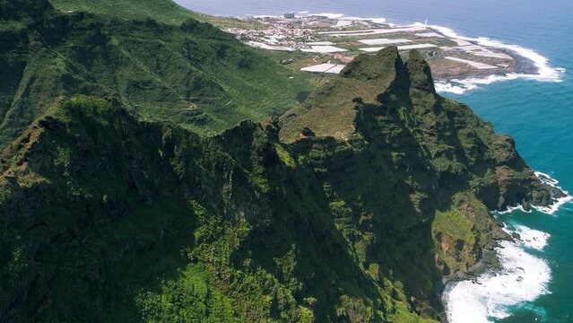 Aerial view of the resort town of Punta del Hidalgo and green mountain ranges on ocean coastline. Coastal cityscape on Tenerife island. Spain.