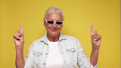 An elderly woman points her finger to attract attention on a beige background