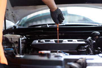 Senior Asian man checking or measuring a vehicle oil engine or engine lubricant level by using oil stick indicator.