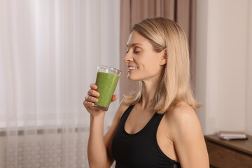 Young woman in sportswear with glass of fresh smoothie at home