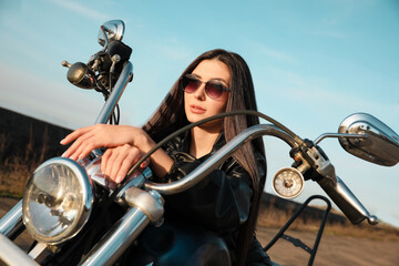 Fototapeta na wymiar Beautiful young woman sitting on motorcycle outdoors