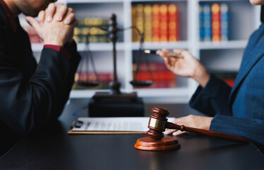 Lawyer working with client discussing contract papers with brass scale about legal legislation.