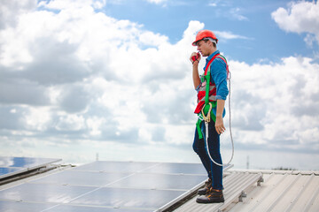 Professional worker cleaning solar panels with brush and washing with water on roof structure of building factory. Technician using mop to clean the dirty and dust, green electricity energy technology