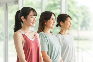 Fototapeta premium スポーツジムでスポーツウェアを着てトレーニングする笑顔の女性達の横顔 